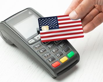 A credit card that looks like an American flag being waved over a chip-reading machine.