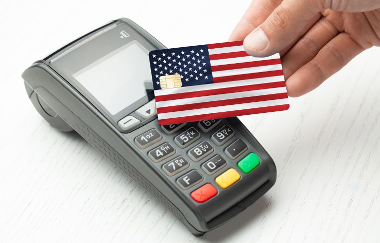 A credit card that looks like an American flag being waved over a chip-reading machine.