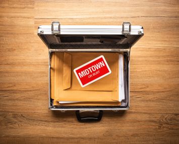 Opened briefcase with a memo that says Midtown on top of some folders.