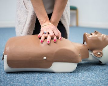 A woman practices first aid on a resuscitation mannequin.