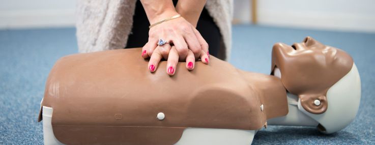 A woman practices first aid on a resuscitation mannequin.