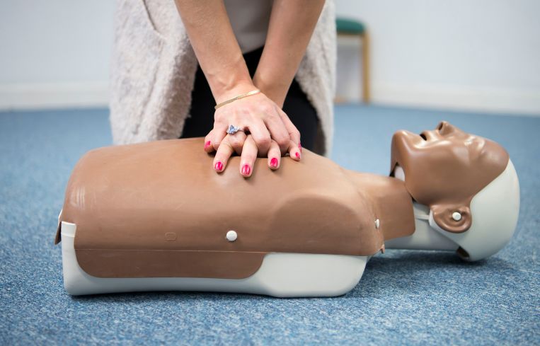 A woman practices first aid on a resuscitation mannequin.