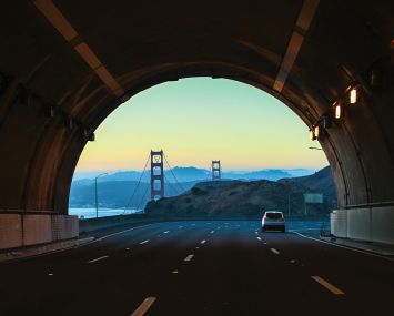 A tunnel ending with a big bridge beyond it.