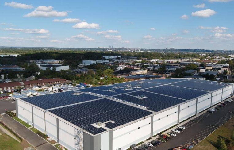 A vast warehouse from the air, with solar panels on top.