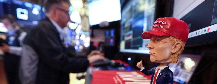 A bobble head depicting President Donald Trump sits on a desk as traders works on the floor of the New York Stock Exchange.