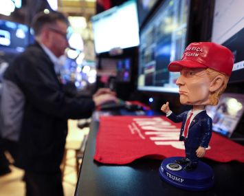 A bobble head depicting President Donald Trump sits on a desk as traders works on the floor of the New York Stock Exchange.