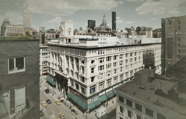 Aerial shot of a large building on a busy urban corner.
