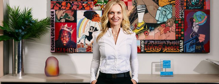 A woman standing in front of a colorful mural.