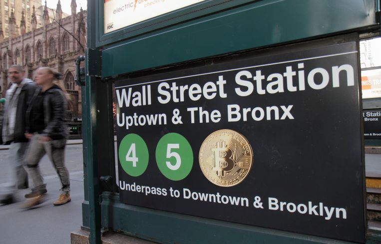 An image of a NYC subway sign, and one of the subway trains is the Bitcoin logo.