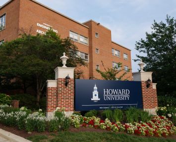 A sign reading "Howard University" in front of a brick building.