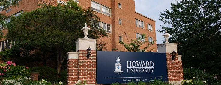 A sign reading "Howard University" in front of a brick building.