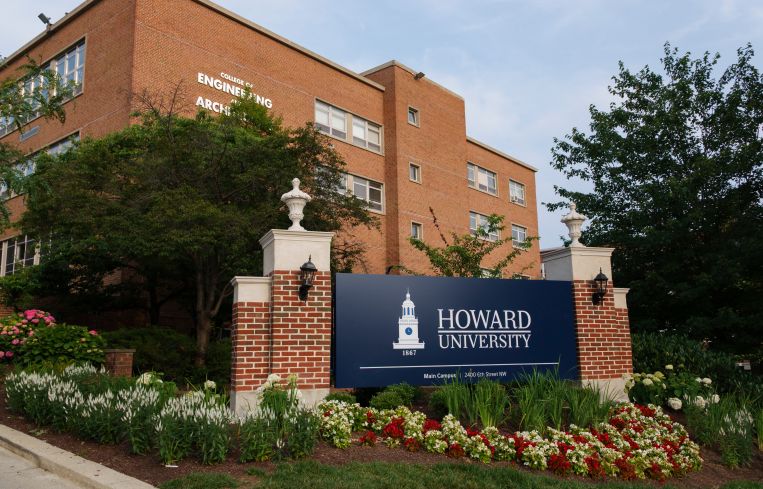 A sign reading "Howard University" in front of a brick building.