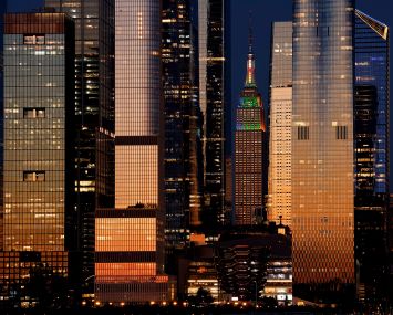 Empire State Building, standing between the towers of Hudson Yards at sunset.