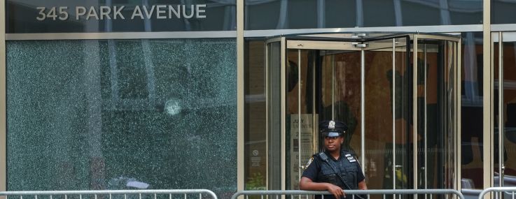 A New York City Police (NYPD) officer stands outside the 345 Park Avenue building, the scene of deadly shootings in Midtown Manhattan.