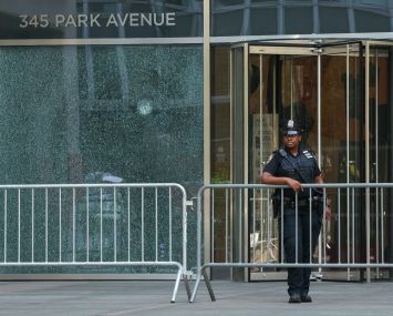 A New York City Police (NYPD) officer stands outside the 345 Park Avenue building, the scene of deadly shootings in Midtown Manhattan.
