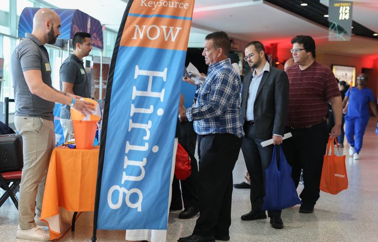 Job seekers wait to speak with a recruiter at the KeySource booth at a job fair in Florida in April.