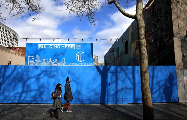 Pedestrians walk past a site to be constructed by Urban Catalyst in San Jose, Calif.