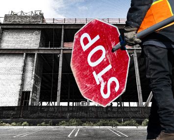 A construction site with someone holding a big stop sign in front of it.
