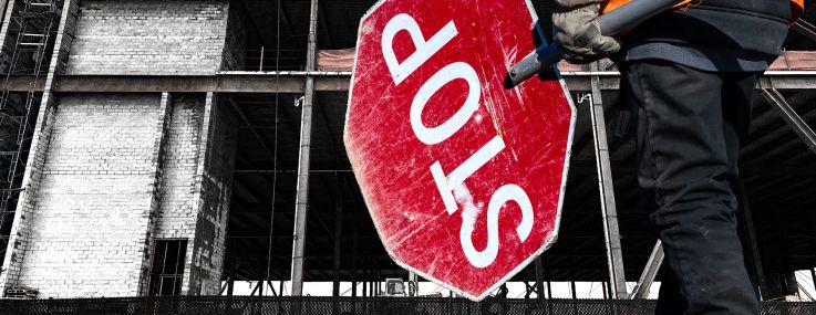 A construction site with someone holding a big stop sign in front of it.
