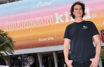 Adam Neumann standing in front of a Flow.Life billboard.
