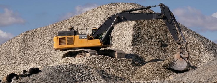 An excavator scoops rocks from a pile.