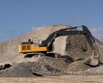 An excavator scoops rocks from a pile.