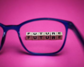 View through isolated blue eyeglasses on word future with pink background (focus on upper row of text).