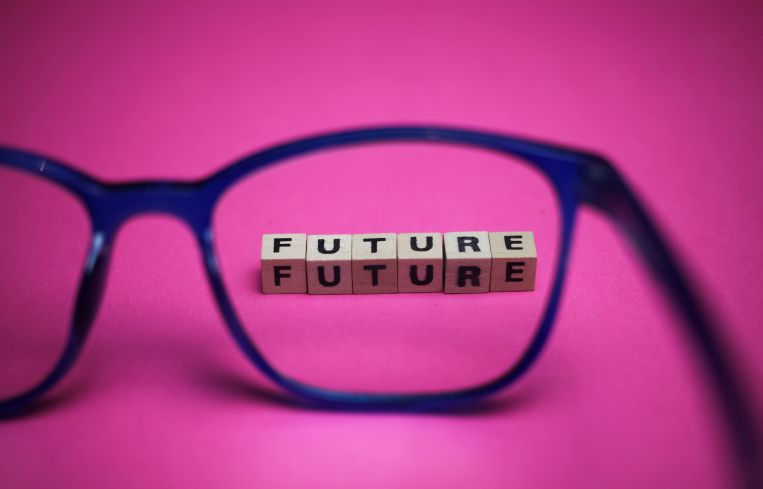 View through isolated blue eyeglasses on word future with pink background (focus on upper row of text).