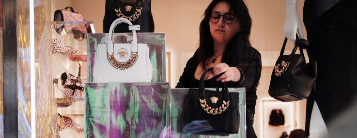 A woman takes down luxury handbags in a windows display in SoHo.