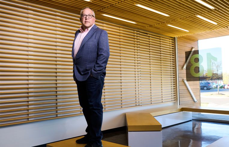A man standing on a slight rise in an office.