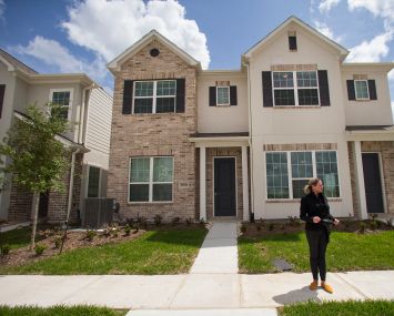 A woman standing in front of a single-family home.
