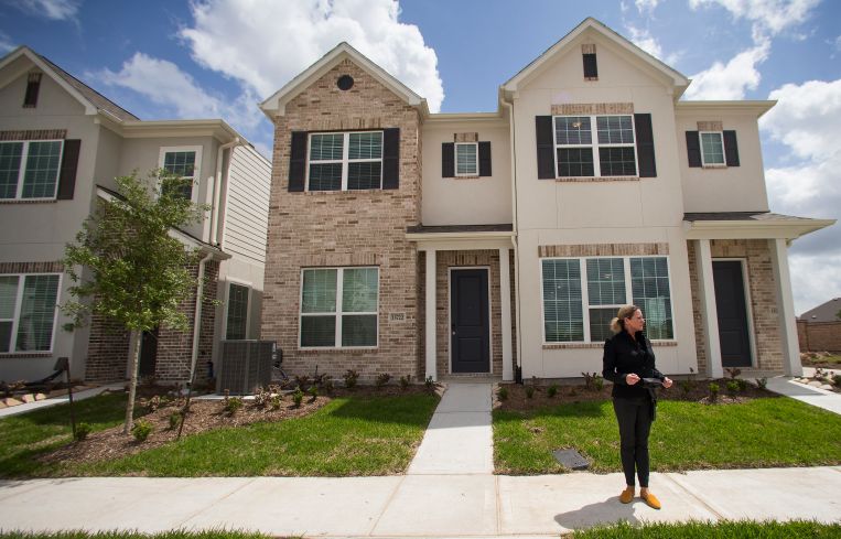 A woman standing in front of a single-family home.