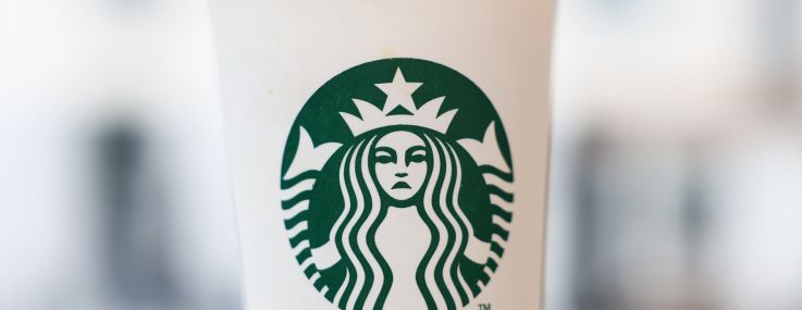 A frowning Starbucks logo on a coffee cup.