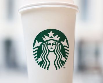 A frowning Starbucks logo on a coffee cup.