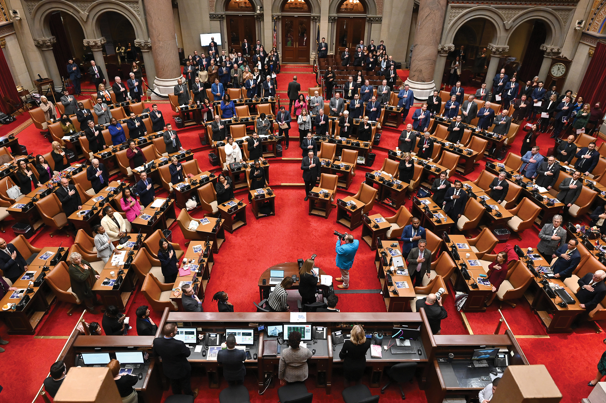 New York Assembly members stand for the Pledge of Allegiance in the Assembly Chamber.