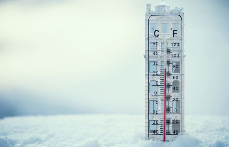 An illustration of a building shaped thermometer stuck in snow.