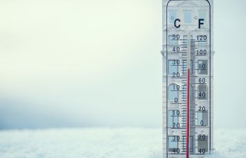 An illustration of a building shaped thermometer stuck in snow.