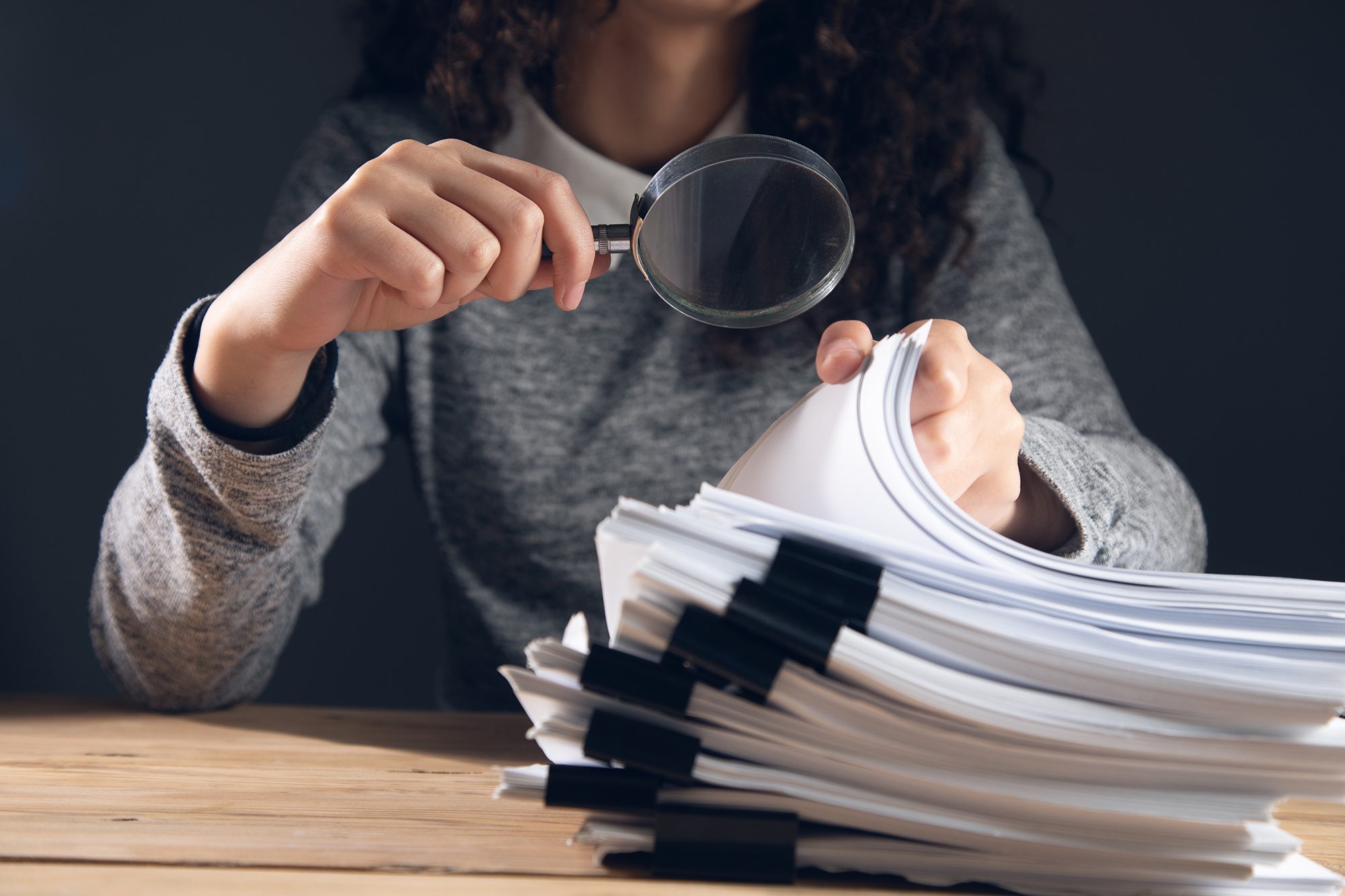 woman holding magnifying glass and documents