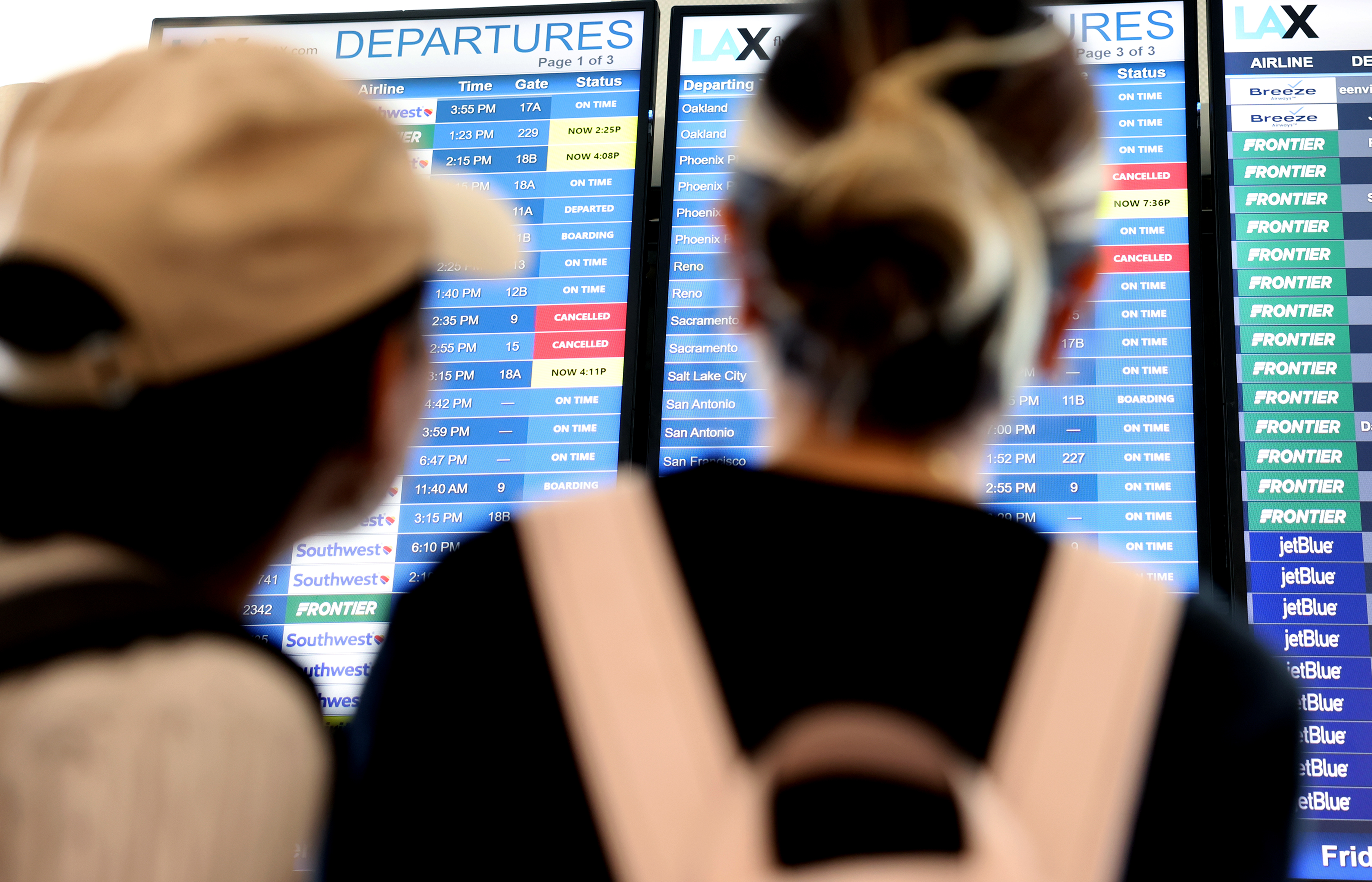Travelers check the flight information display at Los Angeles International Airport.