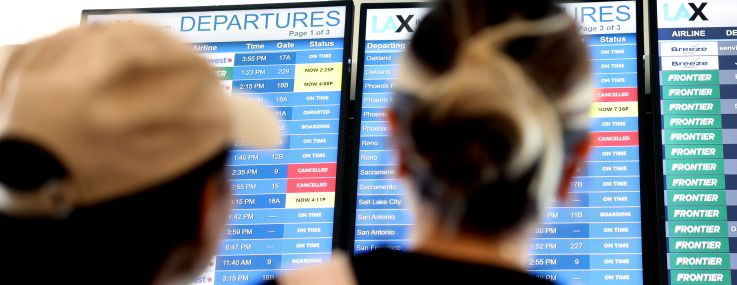 Travelers check the flight information display at Los Angeles International Airport.