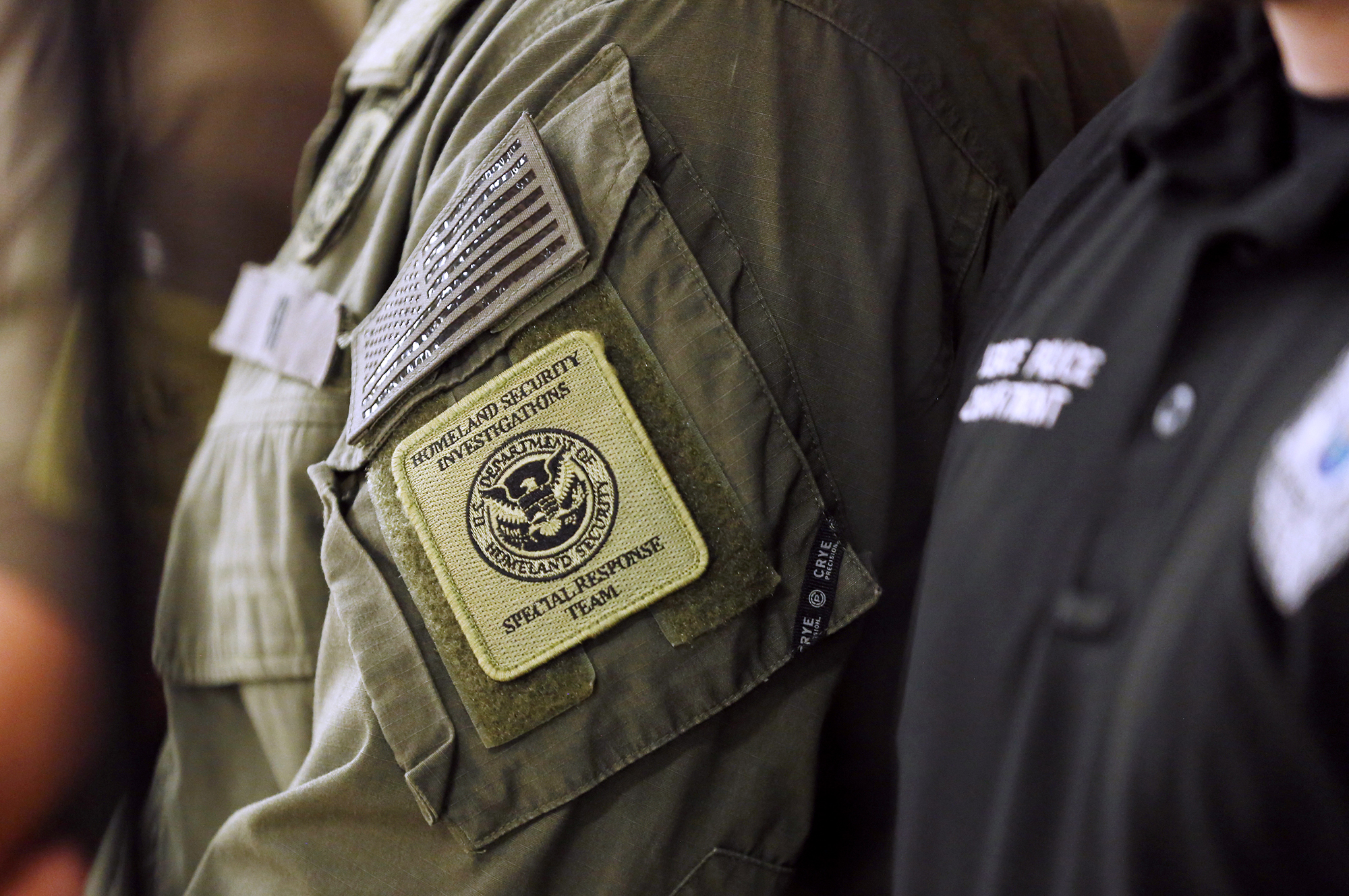 A member of the Homeland Security Investigations Special Response Team stands at press conference.