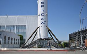 A pedestrian walks past the Falcon 9 Booster at SpaceX in Hawthorne, California.