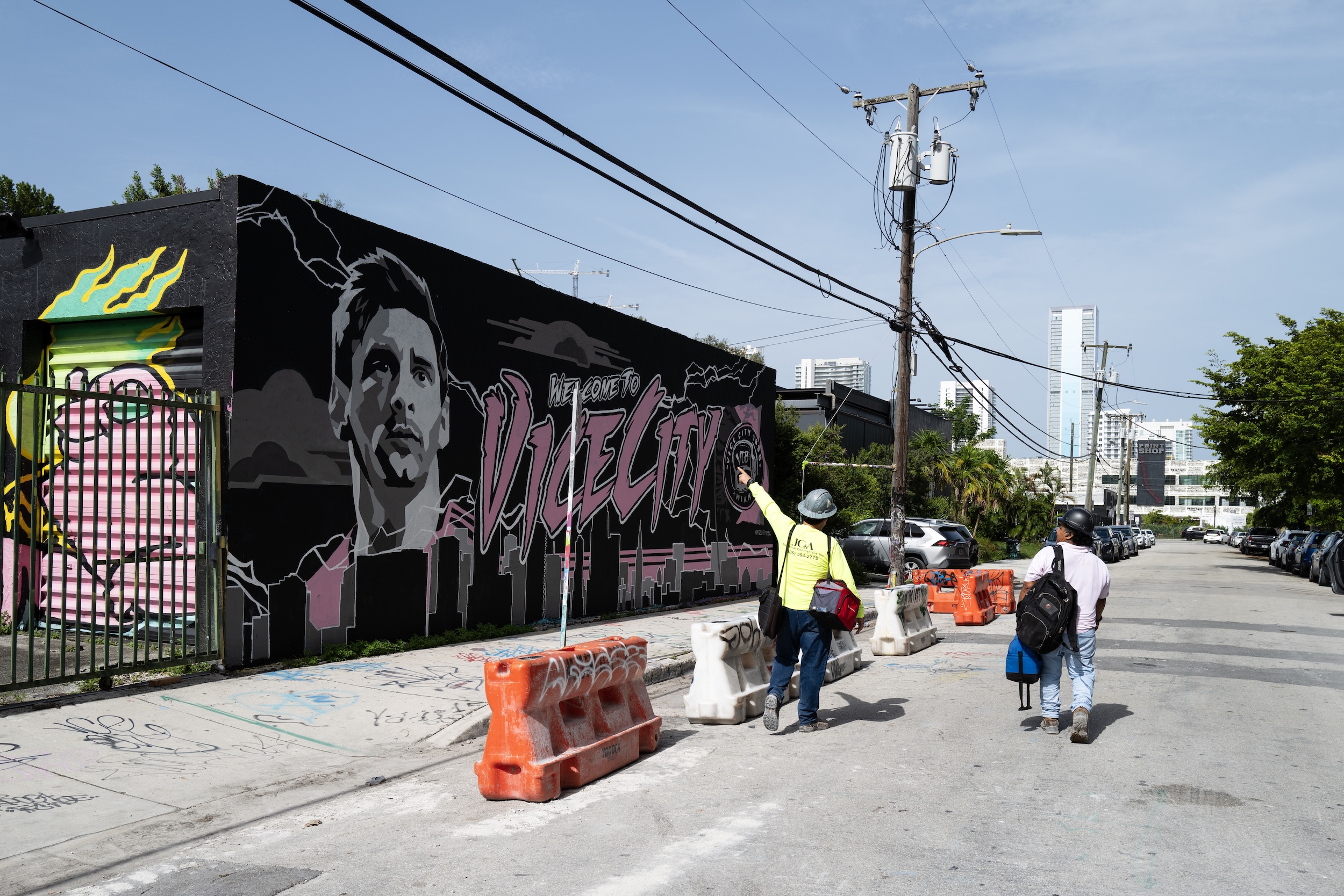 Workmen walk past a Lionel Messi Inter Miami mural artwork in the art district of Wynwood in Miami.