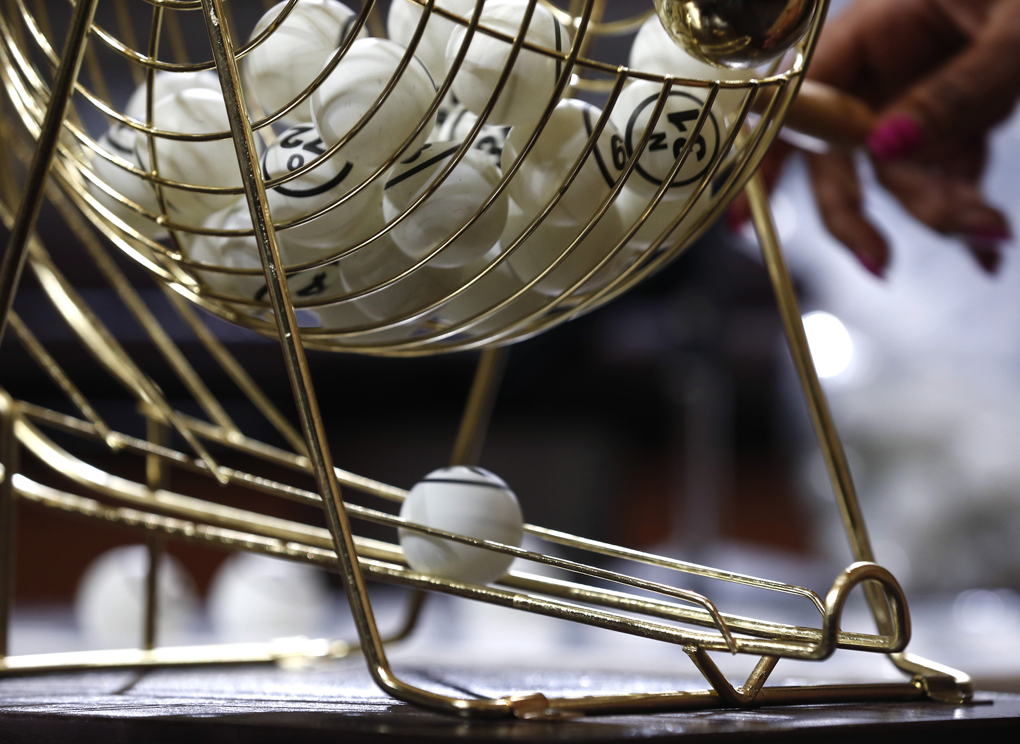 A bingo ping-pong ball rolls out of a hopper.