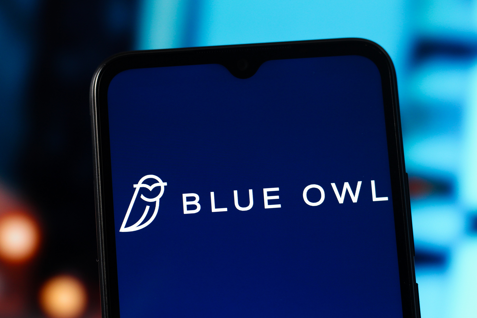 A Blue Owl Capital logo displayed on a mobile phone.
