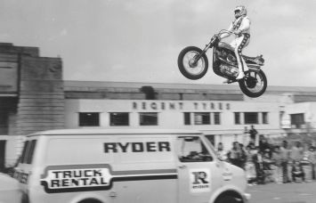 Evel Knievel practising jumping over three vans in the car park of Wembley Stadium.