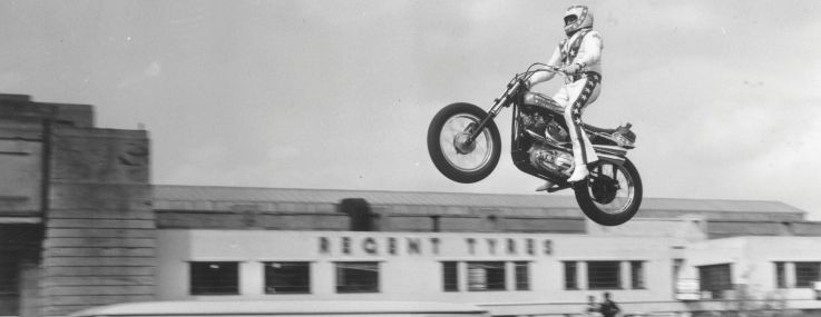 Evel Knievel practising jumping over three vans in the car park of Wembley Stadium.