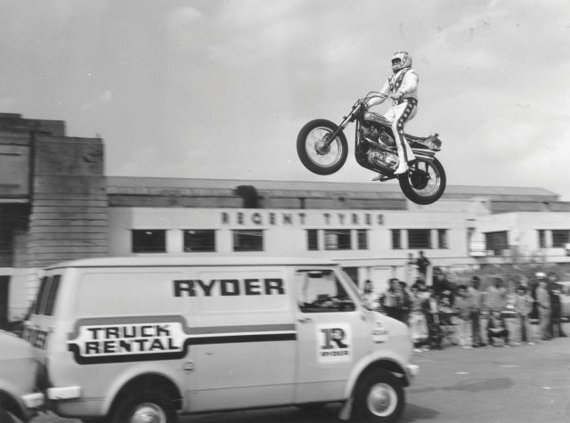 Evel Knievel practising jumping over three vans in the car park of Wembley Stadium.