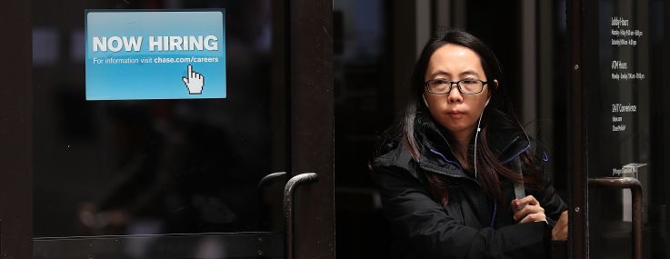 Woman walks by a "Now Hiring" sign at a Chase Bank.