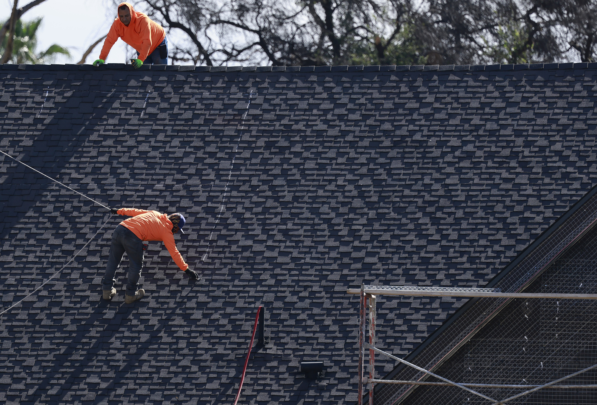 Construction workers rebuild a home in Altadena, Calif.